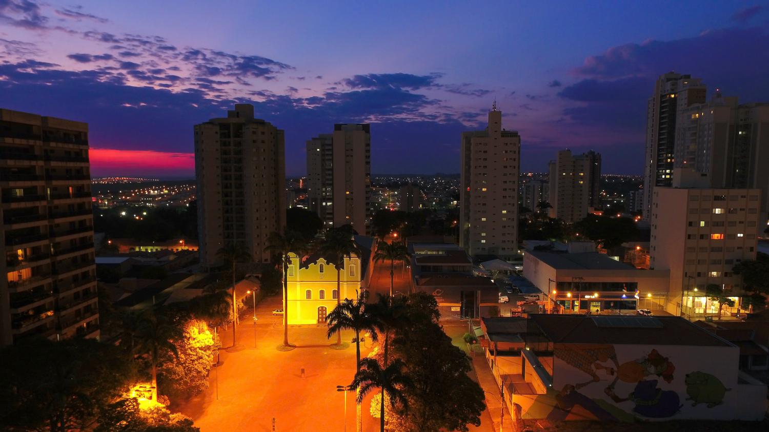 #PraTodosVerem: Fotografia da Igreja Matriz Nossa Senhora da Candelária, em Indaiatuba, com fachada amarela e detalhes brancos, localizada em uma praça arborizada. Palmeiras e outras árvores de copas verdes aparecem em primeiro plano, enquanto prédios residenciais altos compõem o cenário ao fundo com um lindo pôr do sol. #PraTodosVerem: Fotografia da Igreja Matriz Nossa Senhora da Candelária, em Indaiatuba, com fachada amarela e detalhes brancos, localizada em uma praça arborizada. Palmeiras e outras árvores de copas verdes aparecem em primeiro plano, enquanto prédios residenciais altos compõem o cenário ao fundo com um lindo pôr do sol.